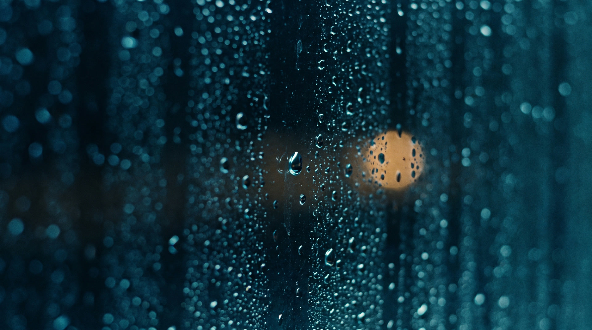 Condensation droplets on dark window glass at night